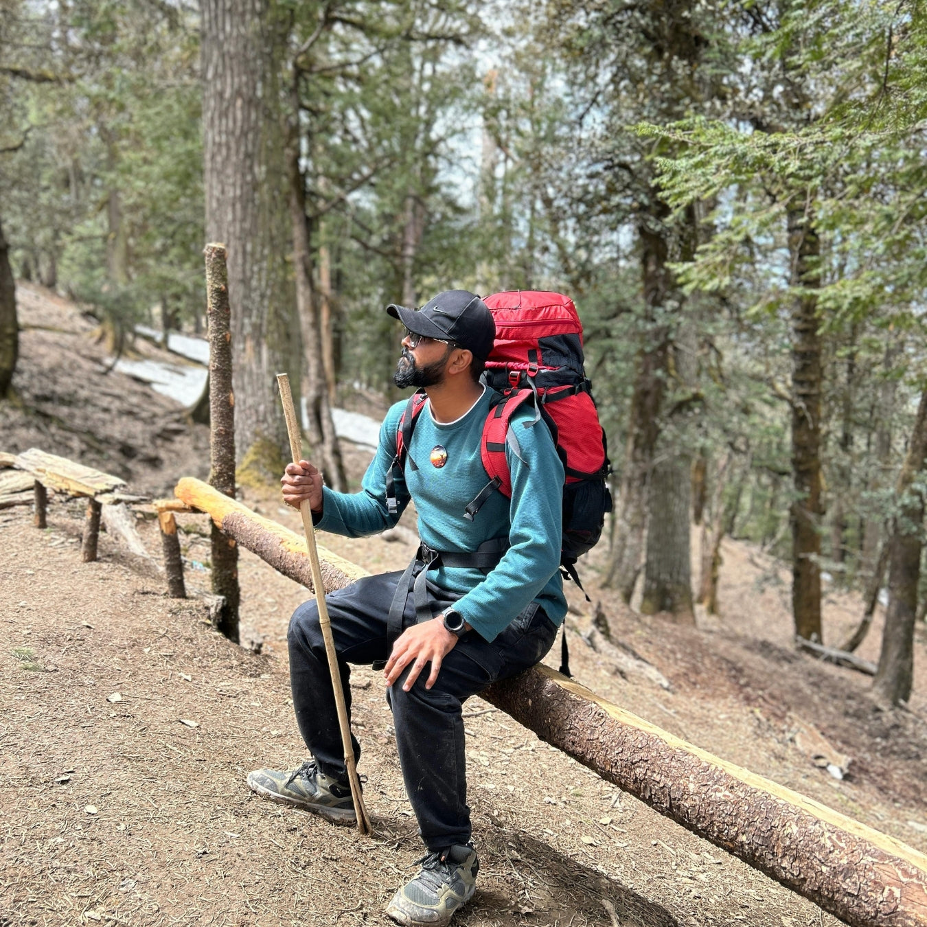 Hiker with a red backpack sitting on a log in a forest