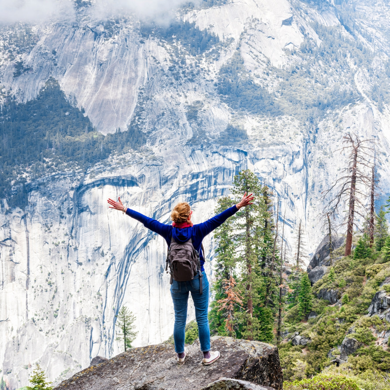 Person with arms outstretched in front of a mountain landscape